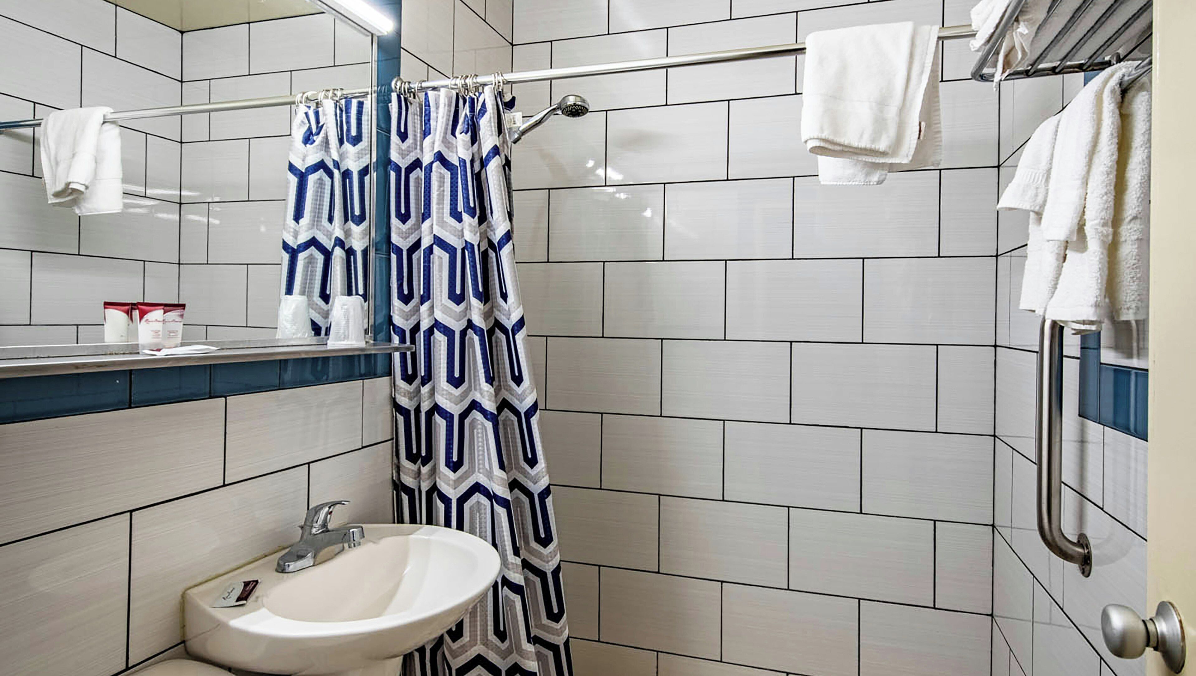 A bathroom with a shower curtain, a sink, and a towel rack.