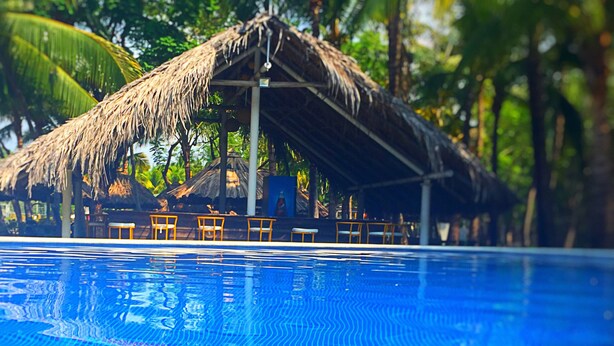 A swimming pool with a thatched-roof structure and chairs in the background. - Puerto Barillas Marina & Lodge (Usulutan)