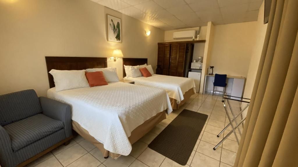 A hotel room with two beds, a sofa, a desk, and a chair.