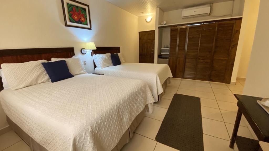 Quarto de hotel com duas camas, mesa de cabeceira, escrivaninha e guarda-roupa.