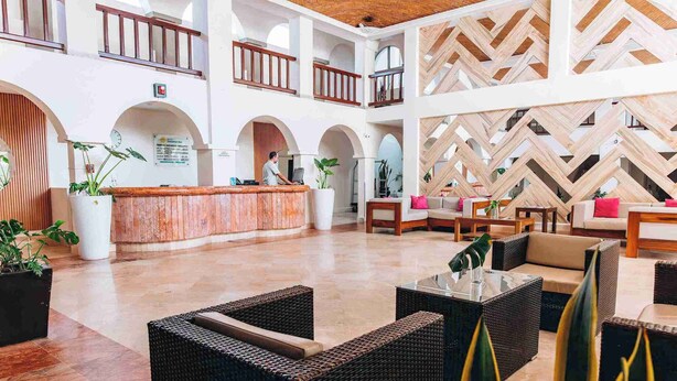 Un'ampia hall con una reception, diverse zone relax e una parete decorativa.