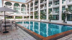 Un hotel con piscina, area salotto all'aperto e un edificio a più piani con balconi.