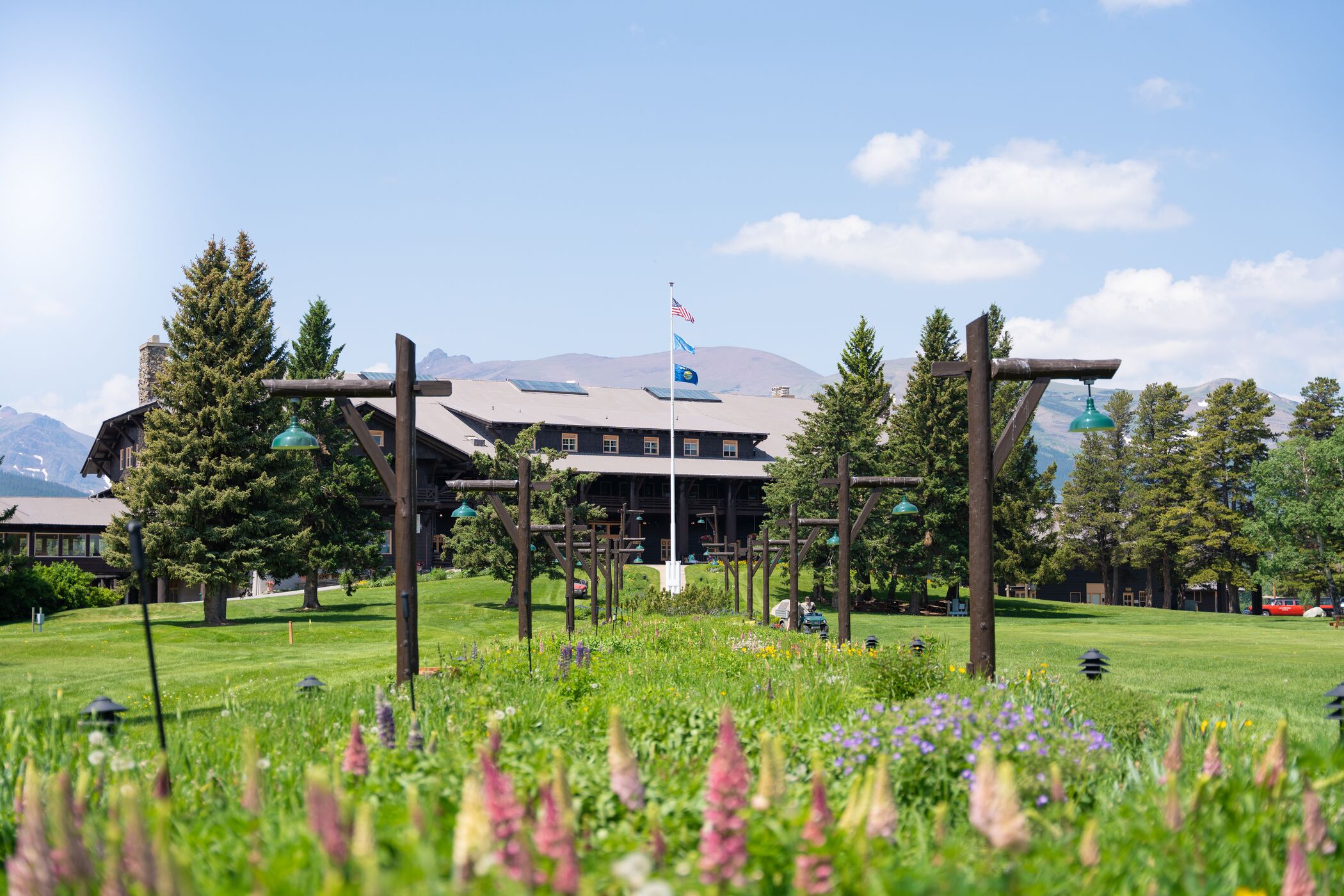 A lodge with a large wooden structure in the foreground, a mountain backdrop, and a clear sky.
