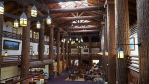 A spacious lodge with high ceilings and wooden beams, featuring multiple dining areas and a central gathering space. - Glacier Park Lodge (East Glacier Park)
