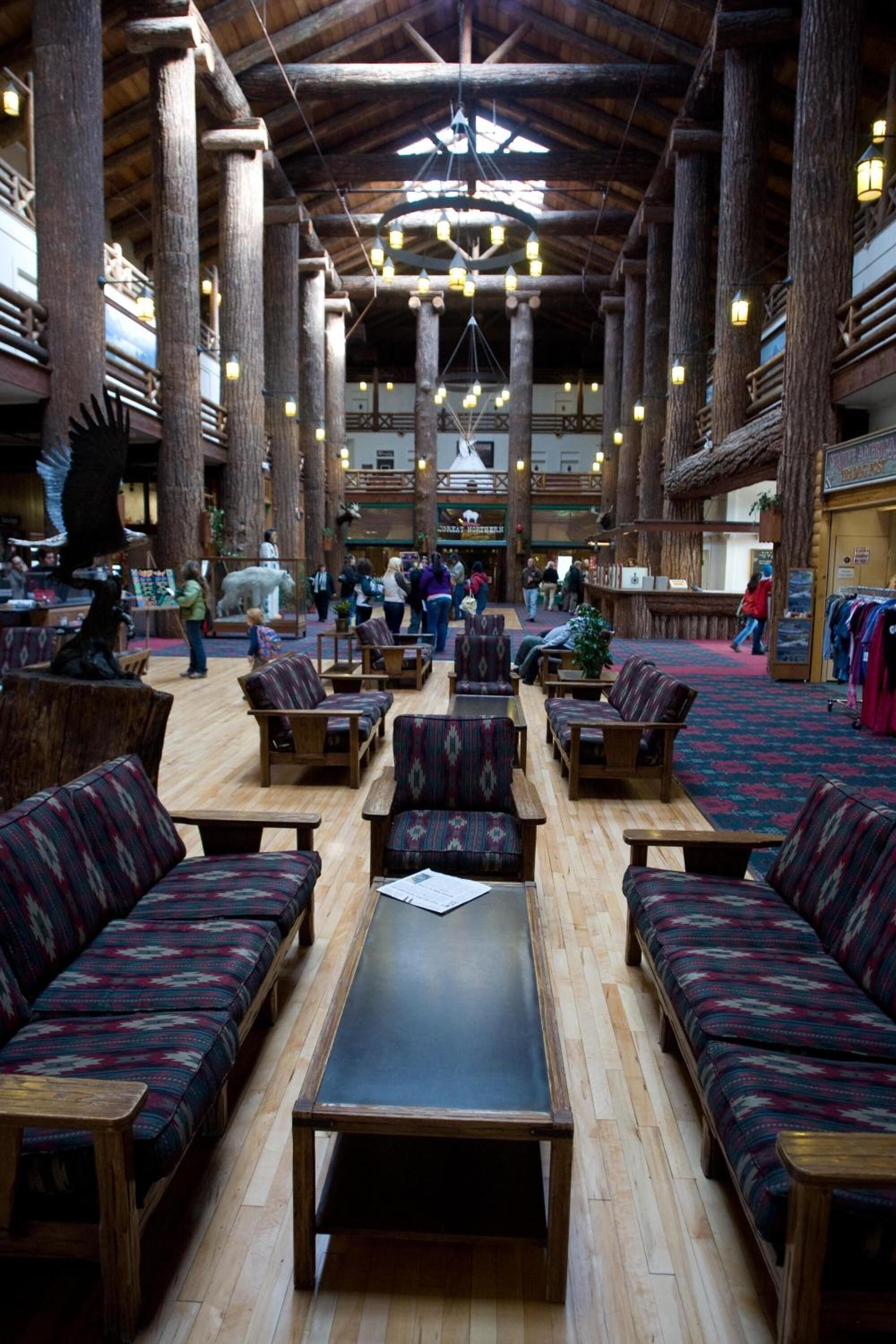 A spacious lobby with high wooden ceilings, large columns, and a central seating area with sofas and tables.