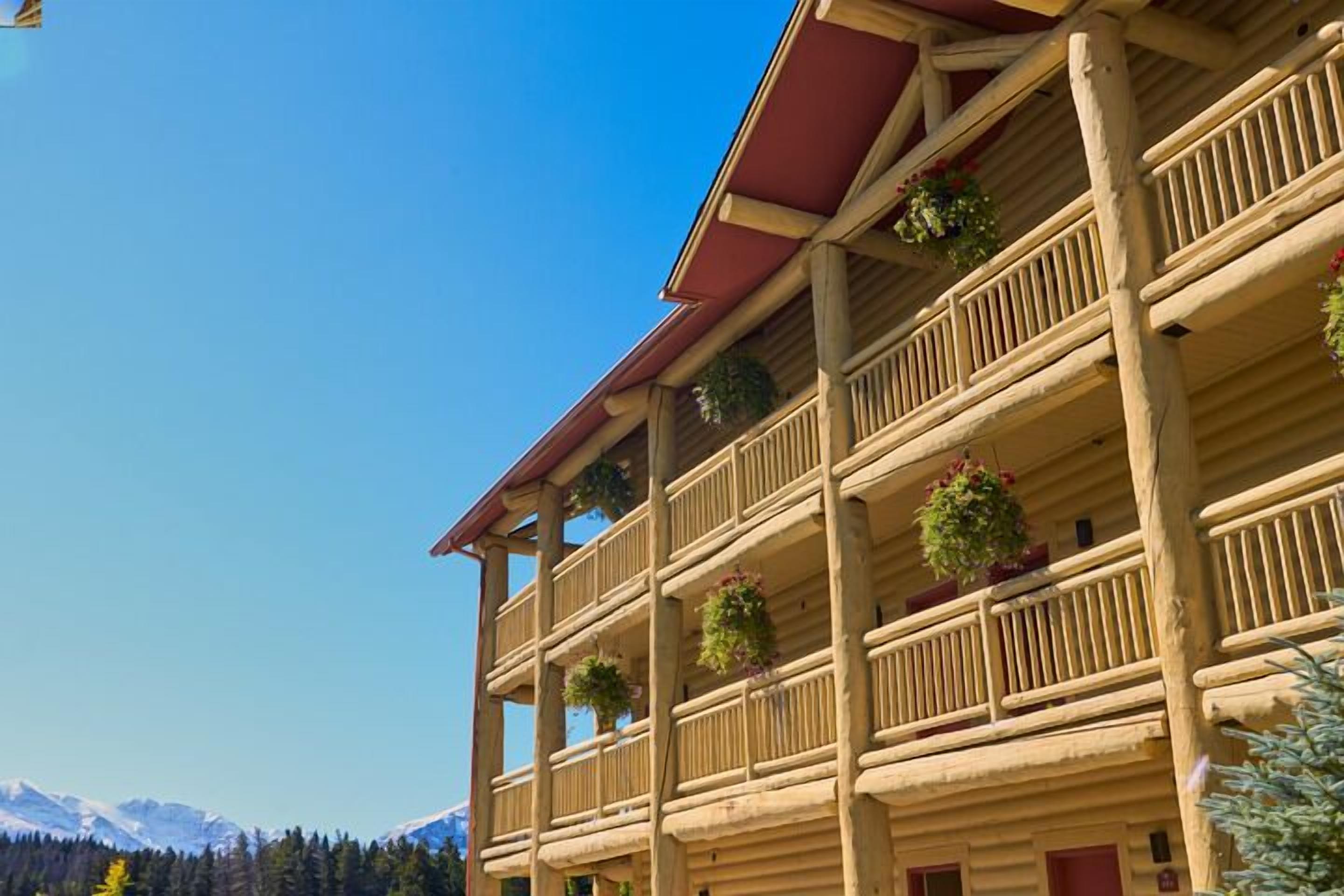 A multi-story wooden building with balconies, each adorned with hanging plants.