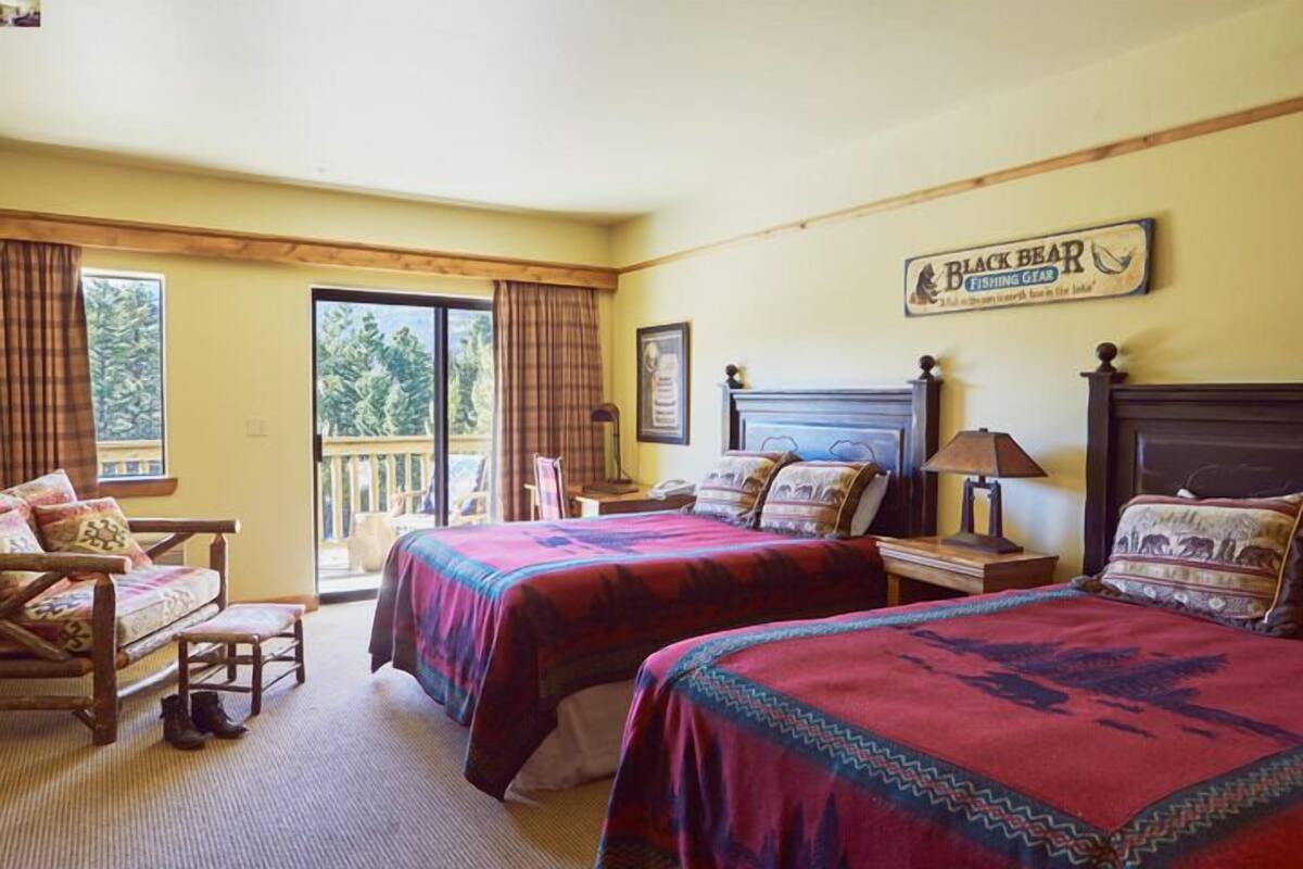 A hotel room with two beds, a sofa, a desk, and a window with curtains.