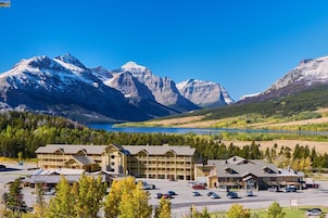 Un albergue con varias edificaciones, un estacionamiento y vistas a montañas y un lago.