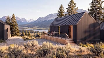 Une cabane dotée d’une terrasse offrant une vue sur un lac et des montagnes.