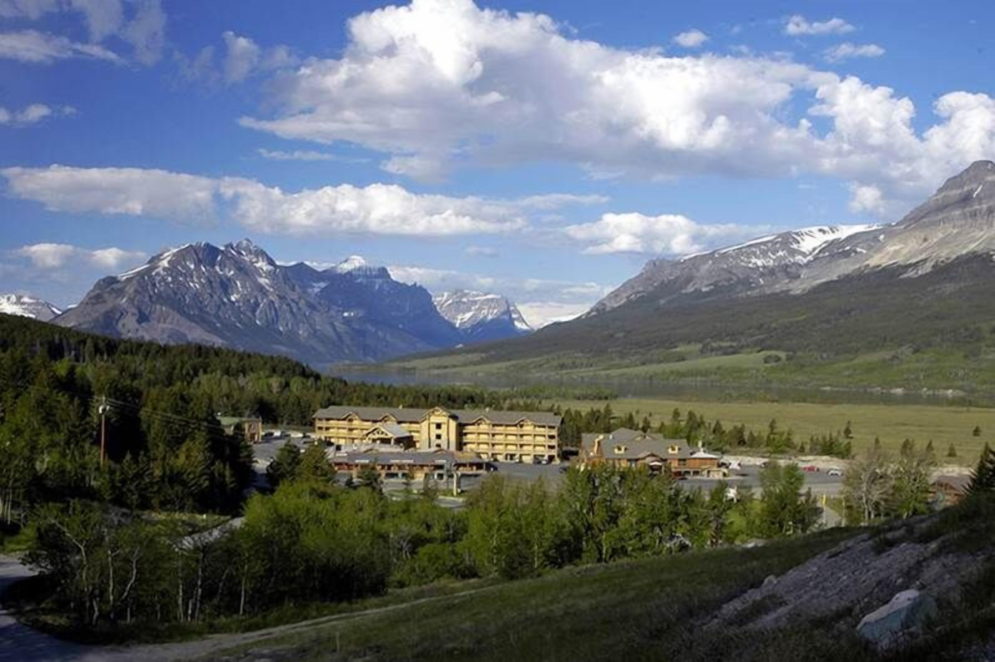 A lodge with multiple buildings, surrounded by mountains and greenery.
