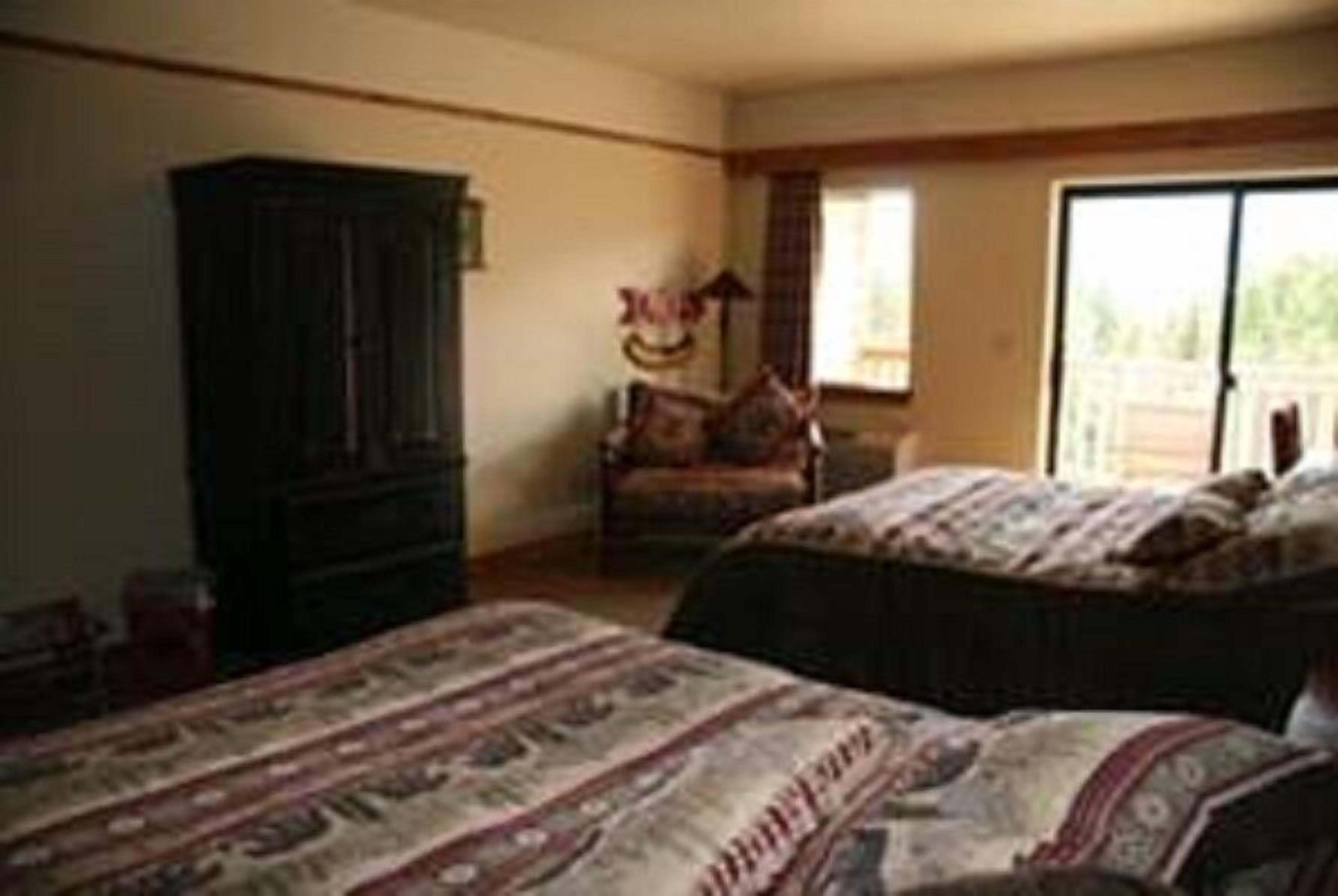 A bedroom with two beds, a wardrobe, and a window with a view.