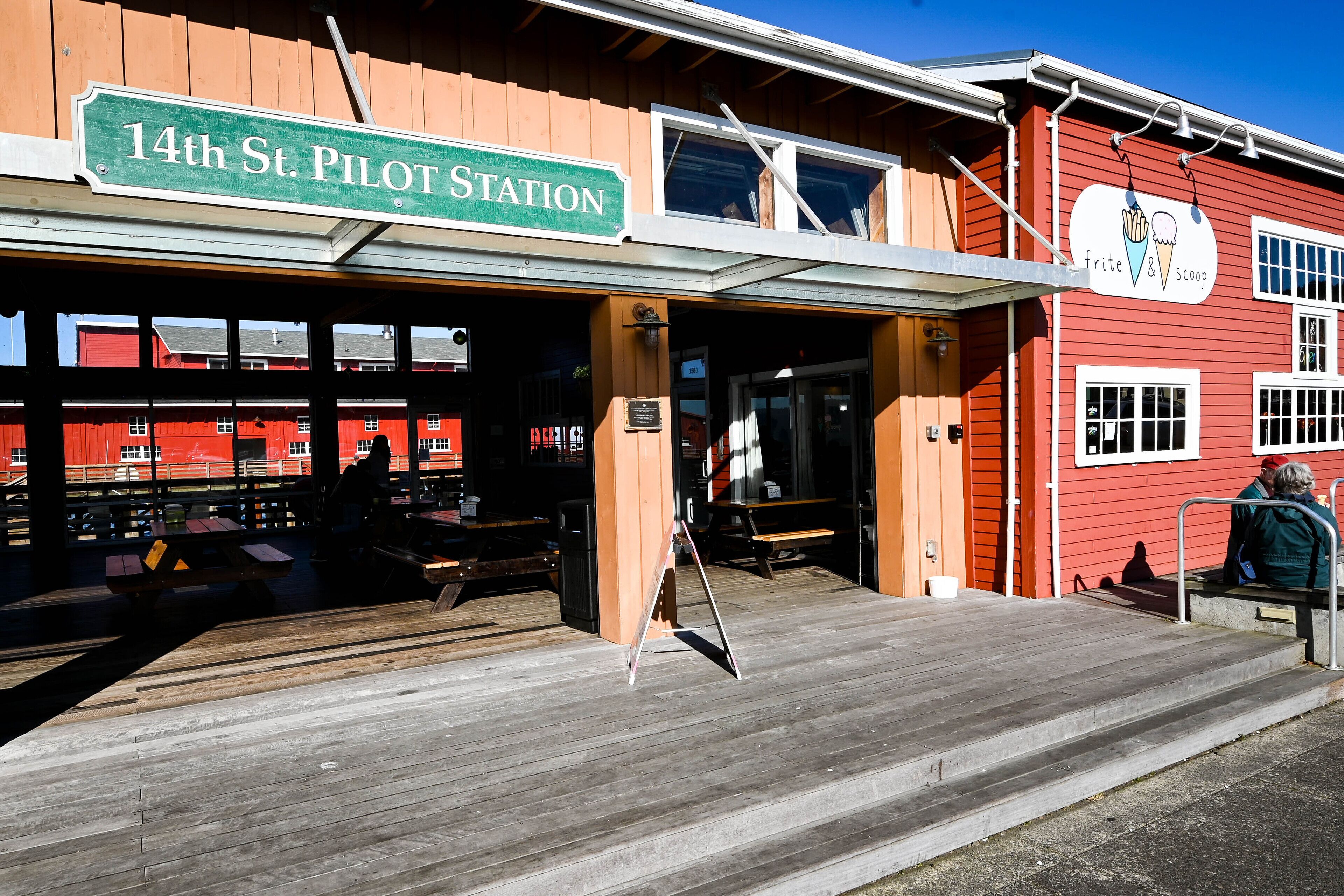 A red building with a sign reading "14th St. Pilot Station" and a sign for "Frite & Scoop."