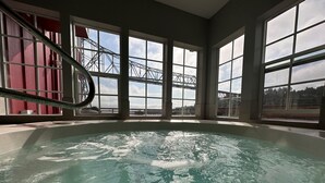 Un bain à remous avec vue sur un pont et des bâtiments, grâce à de grandes fenêtres.