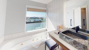 Un baño moderno con una bañera grande, un lavabo de granito y vistas a un puerto deportivo.