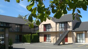 A two-story motel with a parking lot, a staircase to the upper floor, and a sign indicating an office. - Abbella Lodge Motel (Christchurch)