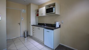 A compact kitchen with a microwave, sink, and a small refrigerator. - Abbella Lodge Motel (Christchurch)