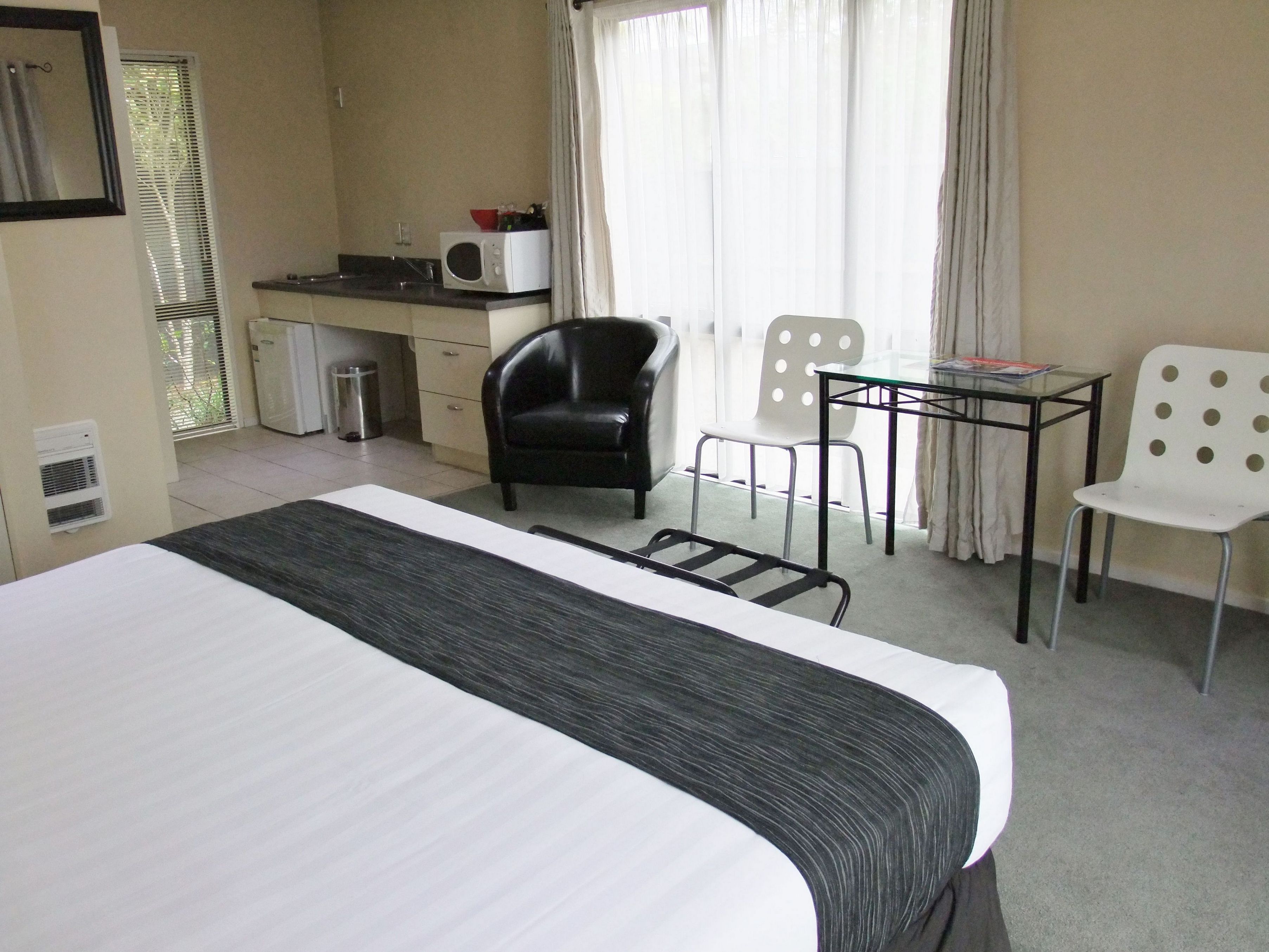 A hotel room with a bed, a desk with a microwave, two chairs, and a small table.