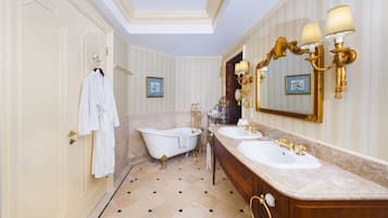 A luxurious bathroom with a clawfoot bathtub, double sinks, and ornate wall sconces.