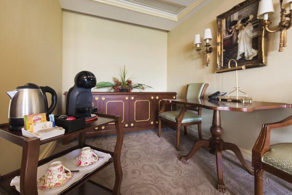 A hotel room with a wooden desk, a coffee maker, a tea set, a chair, and a painting on the wall. - Rocks Hotel (Macau)