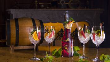 Un bar avec quatre verres remplis d’une boisson aromatisée aux fruits, un grand tonneau en bois et une cheminée décorative en arrière-plan.