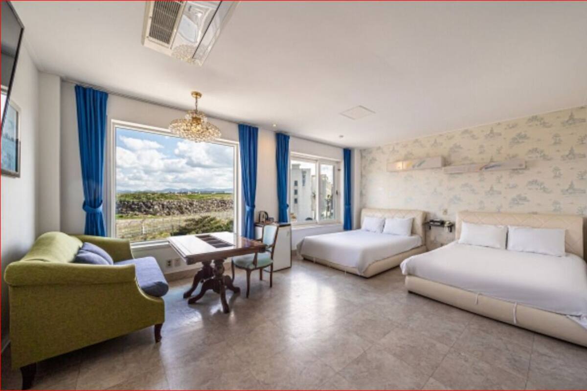 Una habitació d'hotel amb un llit, un sofà, una taula de treball i vistes cap a l'exterior.