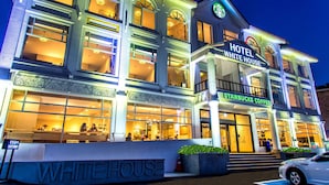 Un hôtel à plusieurs étages qui abrite un café Starbucks au rez-de-chaussée, doté de grandes fenêtres et d’une entrée imposante.