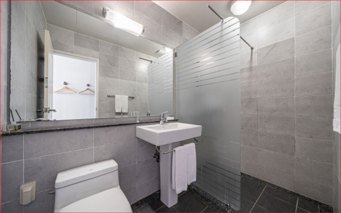 A modern bathroom with a toilet, sink, and shower.