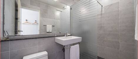 A modern bathroom with a toilet, sink, and shower.