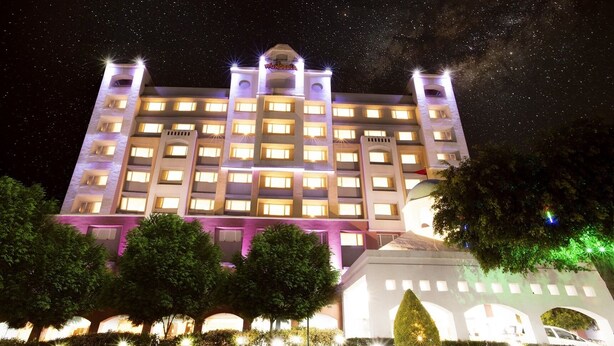 A multi-story hotel with illuminated windows and a central dome structure. - Wonderla Resort (Ramanagara)