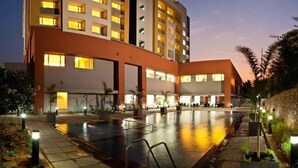 A hotel with multiple floors, a swimming pool, and outdoor seating areas. - Wonderla Resort (Ramanagara)