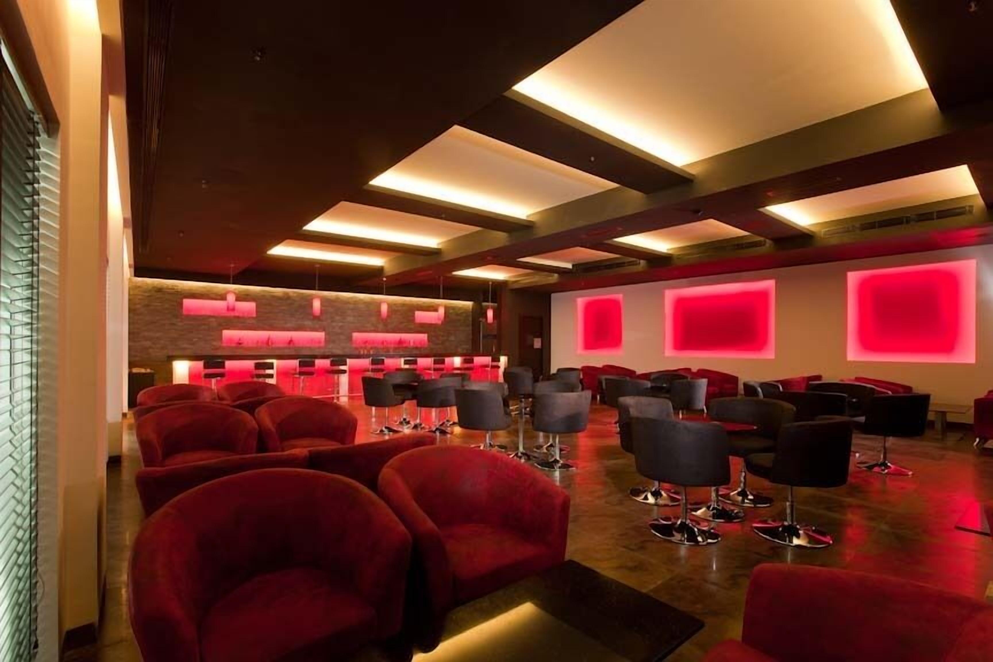 A modern interior with red chairs and a bar area.