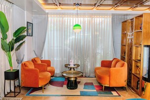 Una sala de estar moderna con sillones naranja, una mesa de centro redonda y una planta grande en maceta.