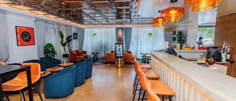 Un intérieur moderne avec un bar, des espaces pour s’asseoir et une vue sur l’extérieur.