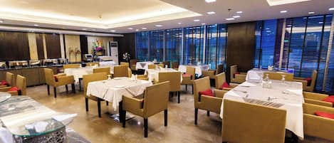 A restaurant with multiple tables and chairs, a buffet area, and large windows.