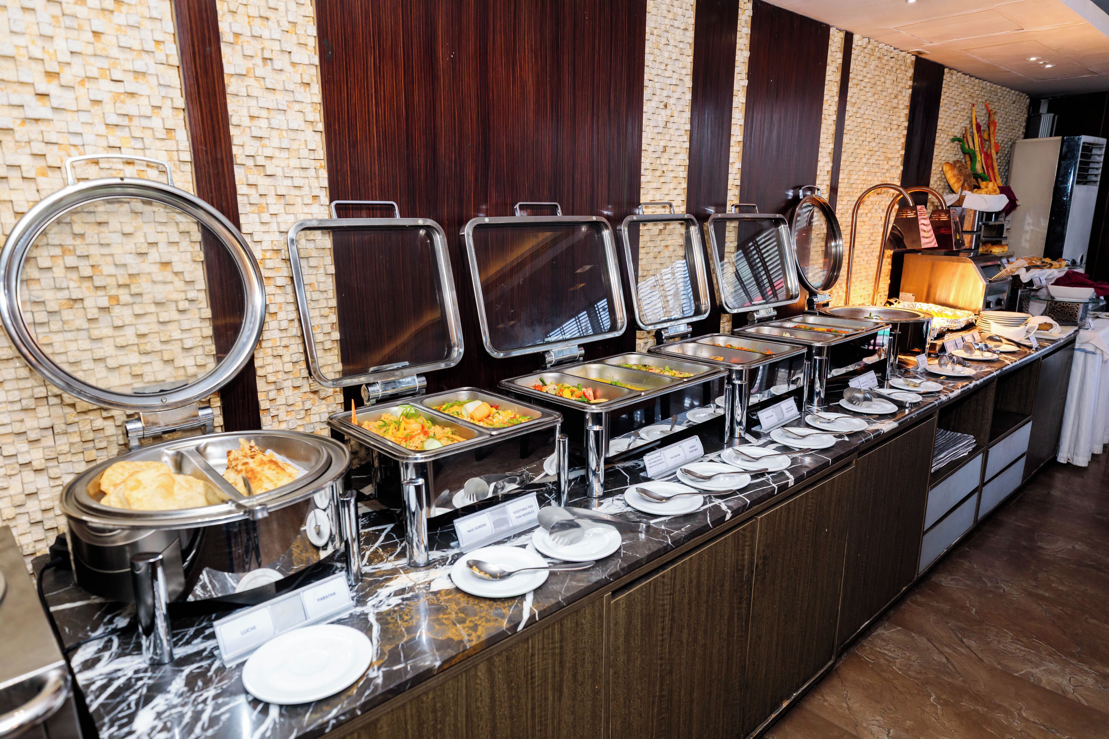 A buffet with various food options, including salads, rice, and other dishes, arranged on a counter with a marble top.