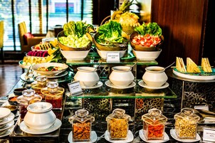 Un bufé con diversas opciones de comida, incluyendo ensaladas, frutas y frutos secos.