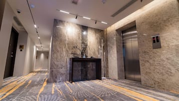 A modern elevator with a digital display, a marble wall, and a patterned carpet.