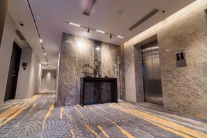 A modern elevator with a digital display, a marble wall, and a patterned carpet. - Best Western Plus Maple Leaf (Dhaka)