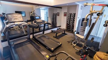 A gym with treadmills, a bench, dumbbells, and a weight machine.