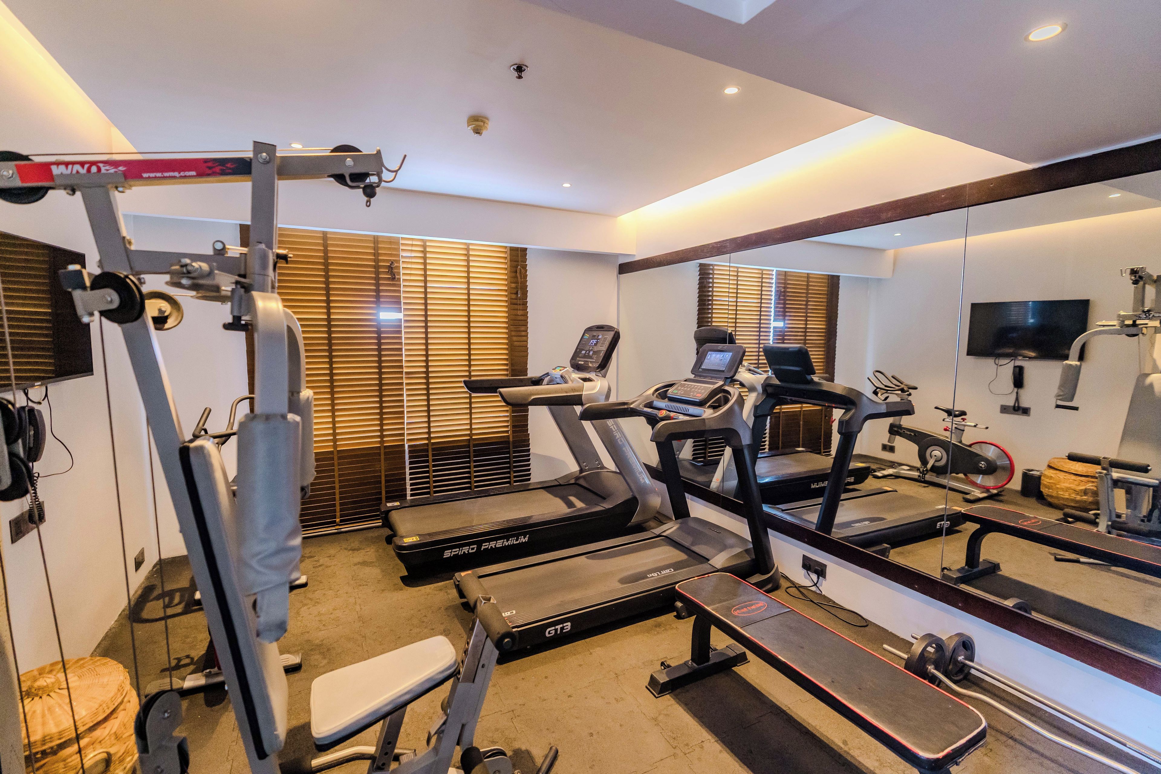 Un gimnasio con cintas de correr, una banca de pesas y equipamiento de ejercicio.