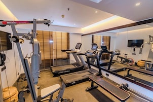 Uma academia com esteiras, um banco de musculação e equipamentos de exercício.