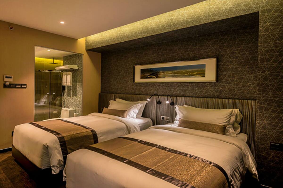 Quarto de hotel com duas camas, área de chuveiro e um quadro na parede.