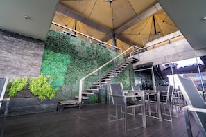 A modern interior with a staircase surrounded by greenery, wooden flooring, and metal railings. - Best Western Plus Maple Leaf (Dhaka)