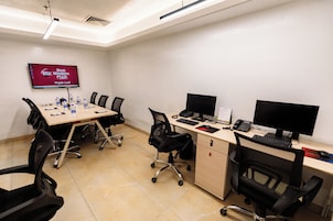Un salón de conferencias con una mesa grande, sillas, una pantalla de televisión y múltiples monitores de computadora.