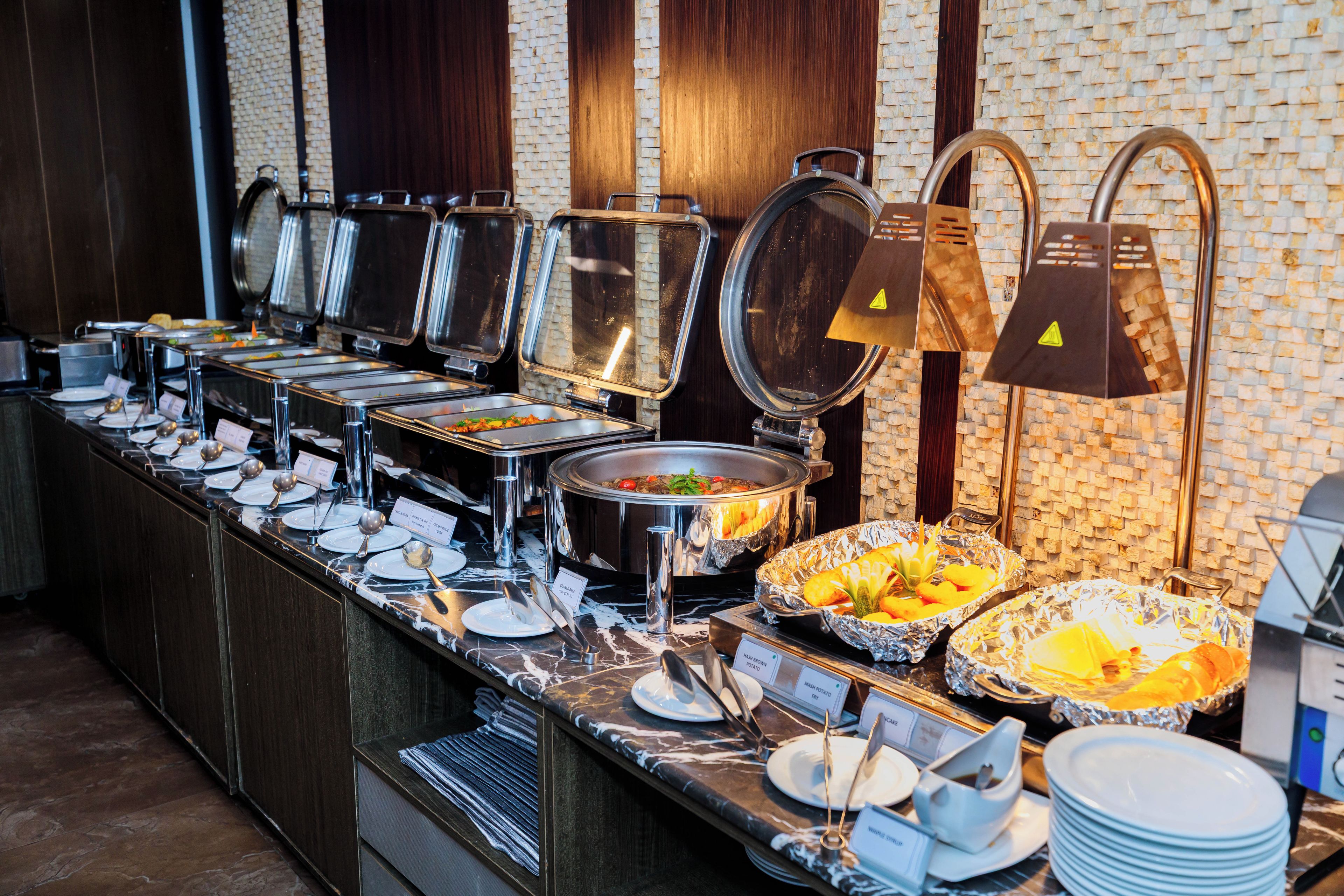 A buffet setup with various food stations, including a salad bar and a fruit display.