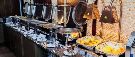 A buffet setup with various food stations, including a salad bar and a fruit display.