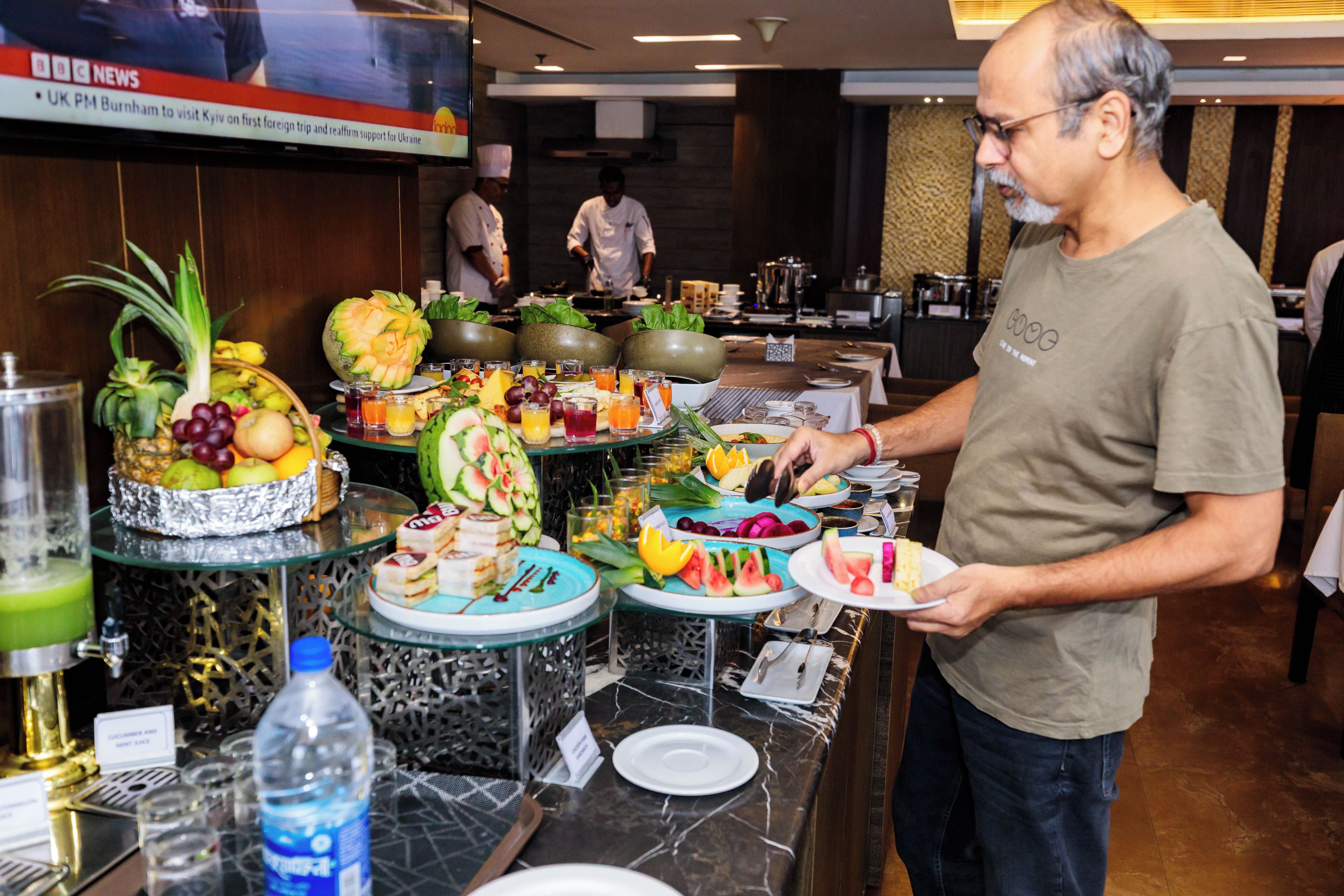 A buffet setup with various food items and a person serving.