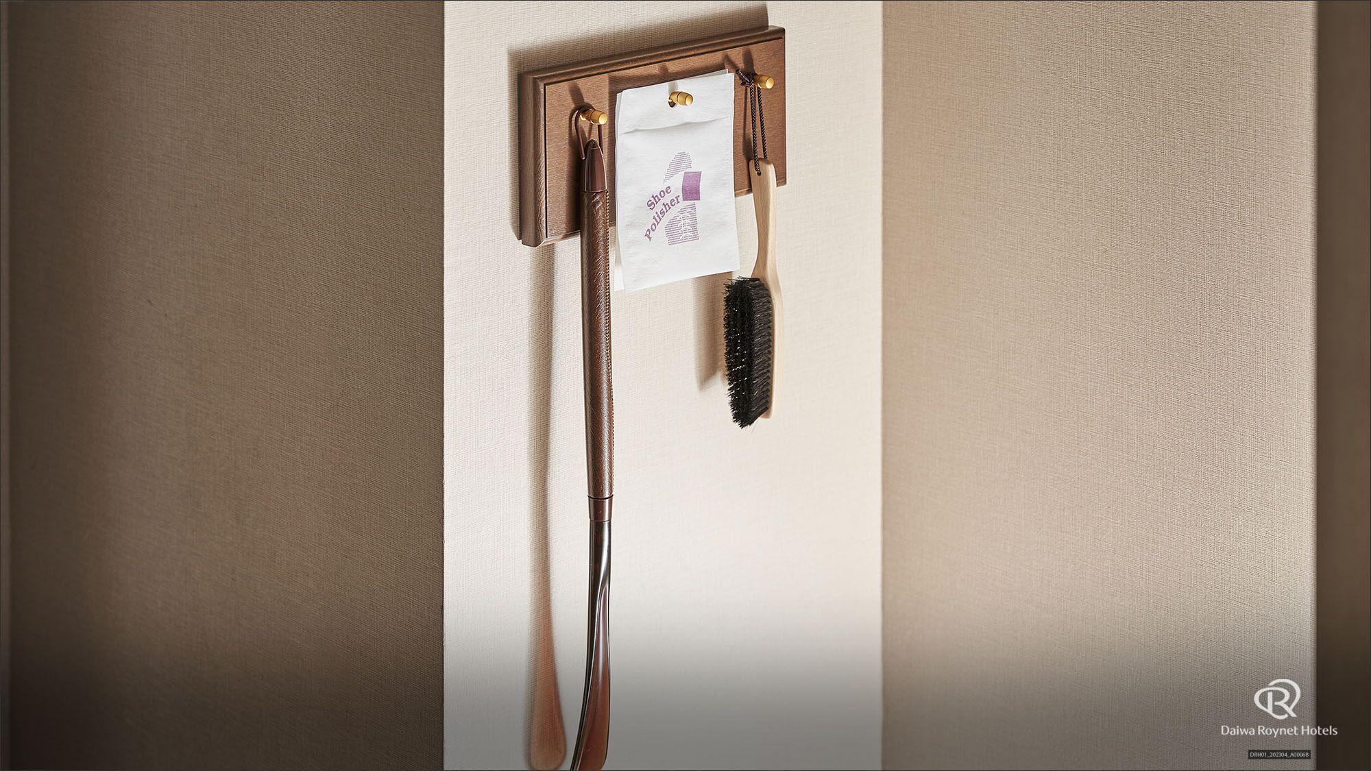 A wall-mounted shoe polish rack with brushes and a label.