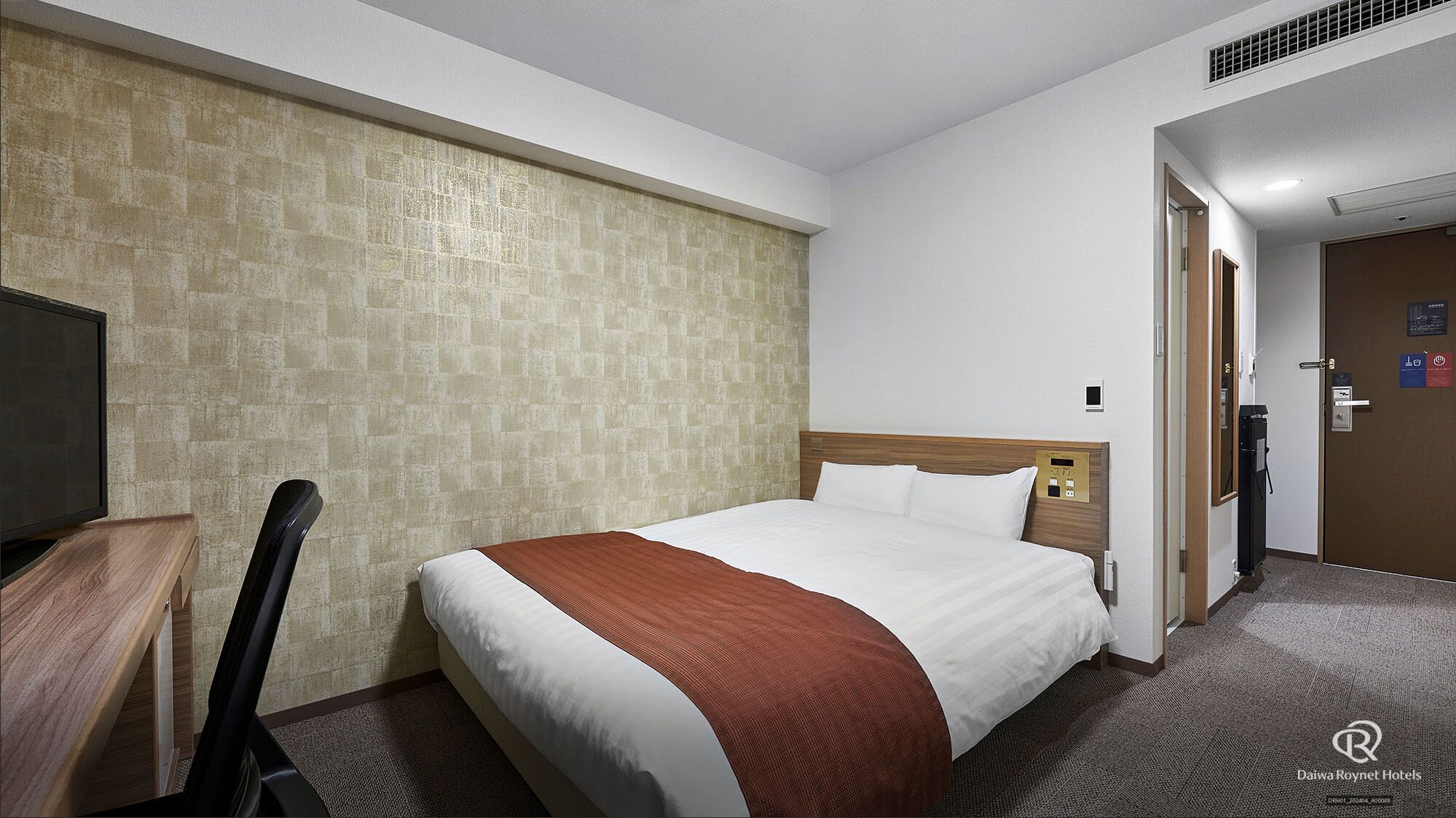 Een hotelkamer met een bed, bureau en televisie.