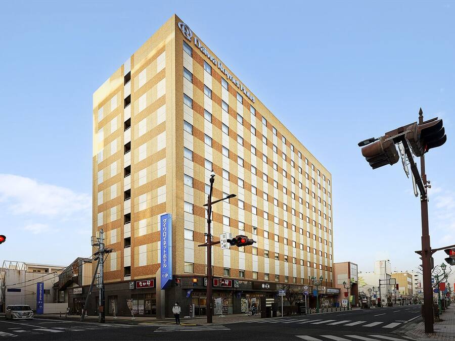 A tall hotel with a checkered facade, multiple floors, and a prominent signage for Daiwa Roynet Hotels.
